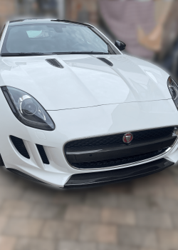 Aufbereiteter weißer Jaguar in makellosem Zustand, glänzend reflektierend unter Sonnenlicht, Symbol für Luxus und Premium-Fahrzeugaufbereitu
