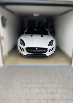 Frontansicht des aufbereiteten weißen Jaguars in einer Garage, kraftvolle Präsenz mit scharfem Grill und glänzenden Scheinwerfern.